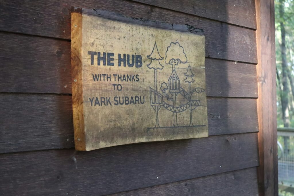 Rustic outdoor wooden sign displayed in natural setting.
