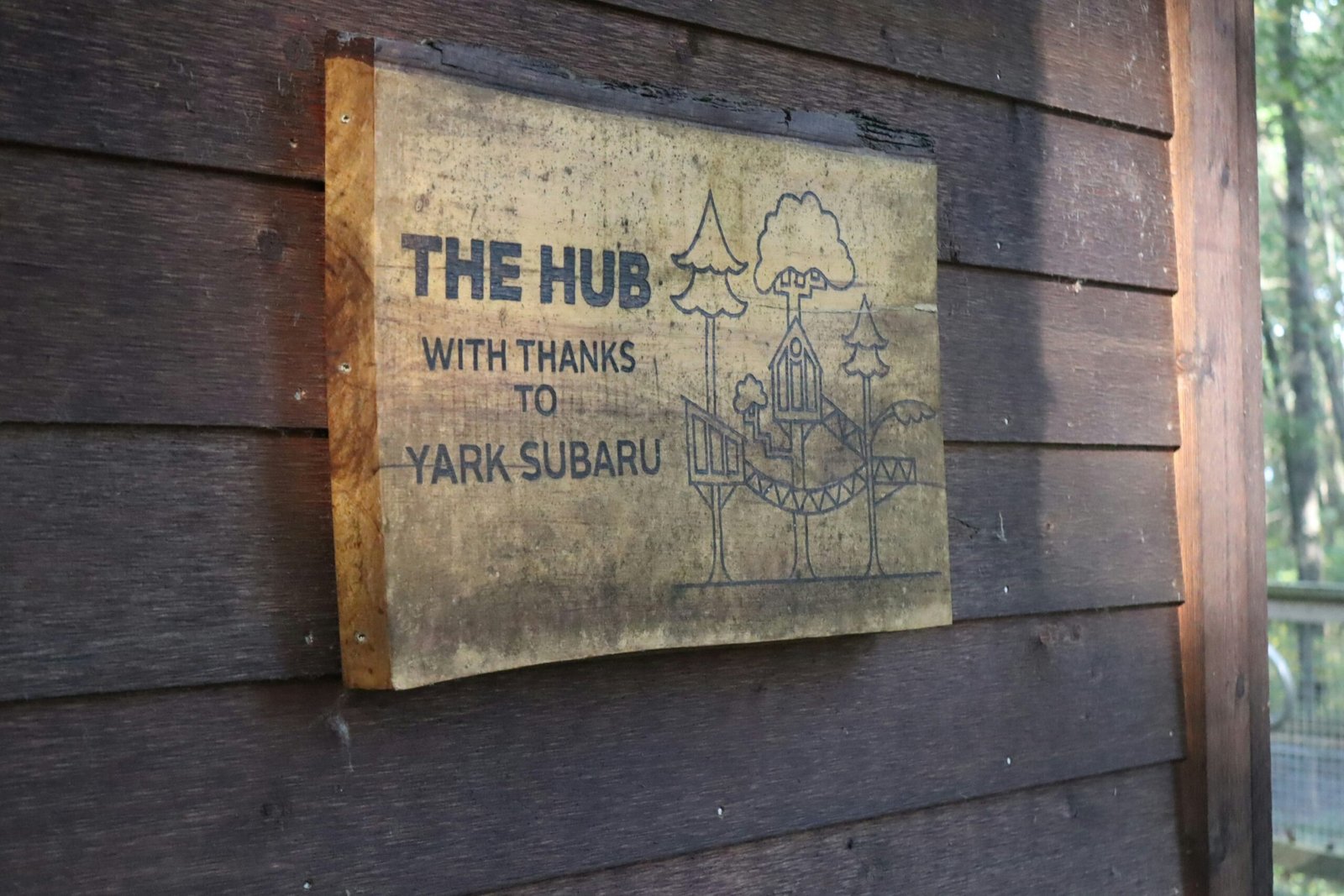 Rustic outdoor wooden sign displayed in natural setting.